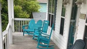 Eine Veranda mit drei Schaukelstühlen und einer Holzterrasse.