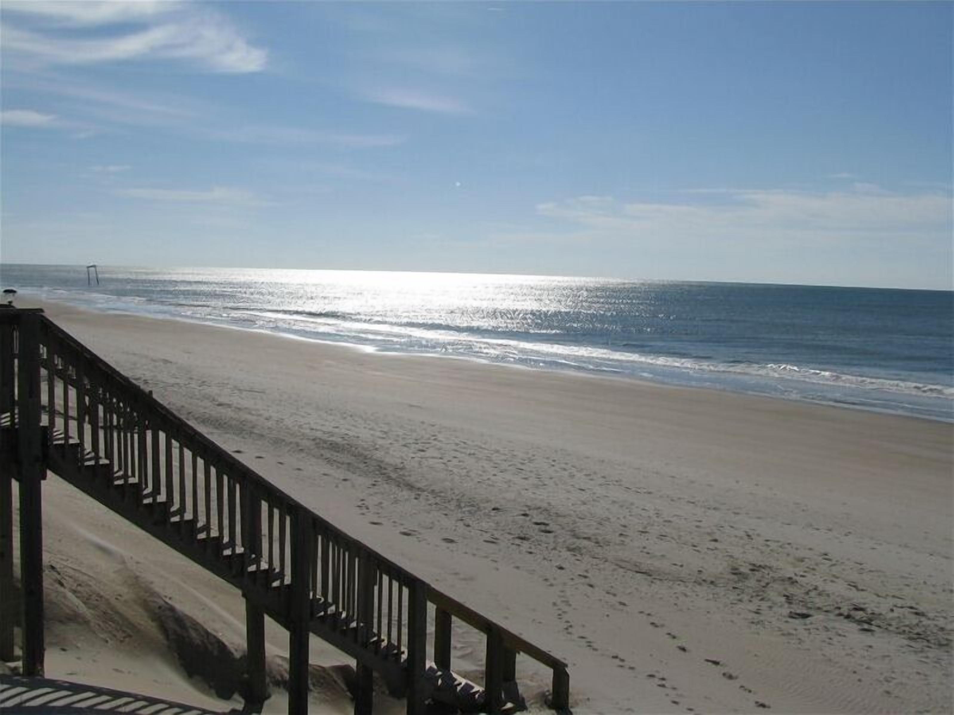 A beach with a wooden walkway leading to the water.