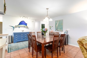 Un comedor con mesa y sillas de madera, un aparador azul y una escultura decorativa de pez.