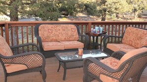 A deck with wicker furniture, including a sofa and chairs, and a glass table with a candle. - Golden Escape- Private Hot tub, Dog Friendly (Redmond)
