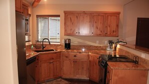 A kitchen with wooden cabinets, granite countertops, a dishwasher, a coffee maker, and a stove. - Golden Escape- Private Hot tub, Dog Friendly (Redmond)