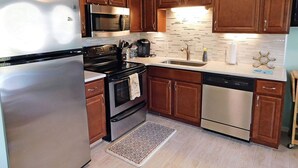 A kitchen with wooden cabinets, stainless steel appliances, a microwave, stove, sink, and a dishwasher. - Ocean View Villa with Amazing Resort Amenities -- just steps from the beach!!! (Hilton Head Island)