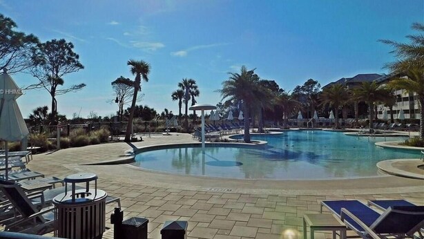 A pool area with lounge chairs, palm trees, and a clear sky. - Ocean View Villa with Amazing Resort Amenities -- just steps from the beach!!! (Hilton Head Island)