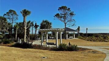 A gazebo with a patio, palm trees, and a building in the background.