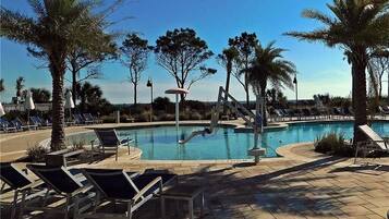 Relax by the pool surrounded by palm trees and lounge chairs on a spacious patio.