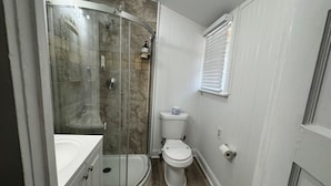 Une salle de bain avec une douche à parois de verre, des toilettes et un lavabo.