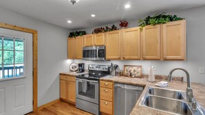 A modern kitchen with wooden cabinets, stainless steel appliances, and a granite countertop. - 4BR + Kid Sleep area-“Bunkhouse”=5BR-3BA-Sleeps 12 (Sevierville)