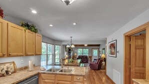 A spacious kitchen with wooden cabinets, granite countertops, and a central island. - 4BR + Kid Sleep area-“Bunkhouse”=5BR-3BA-Sleeps 12 (Sevierville)