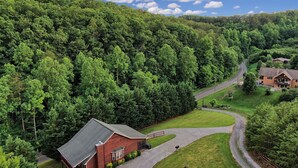A red building with a sloped roof, surrounded by a well-maintained lawn and a winding road. - 4BR + Kid Sleep area-“Bunkhouse”=5BR-3BA-Sleeps 12 (Sevierville)