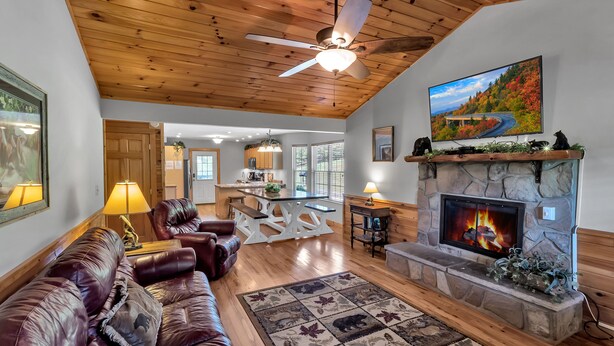 A cozy living room with a fireplace, leather sofa, and a stone fireplace surround. - 4BR + Kid Sleep area-“Bunkhouse”=5BR-3BA-Sleeps 12 (Sevierville)