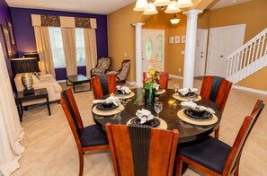 A dining room with a round table set for six, surrounded by wooden chairs with dark cushions. - 5BR Villa • South-Facing Pool & Spa • No Rear Neighbours • Near Disney (Davenport)