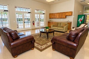A spacious living room with leather sofas, a coffee table, and a view through large glass doors to an outdoor area. - 5BR Villa • South-Facing Pool & Spa • No Rear Neighbours • Near Disney (Davenport)