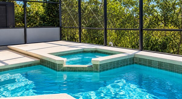 A swimming pool with a geometric design, surrounded by a balcony with a view of trees.