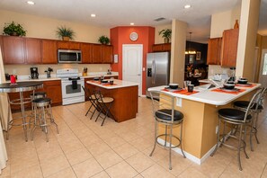 A modern kitchen with wooden cabinets, stainless steel appliances, and a central island with bar stools.