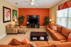 A living room with a sofa set, a coffee table, a flat-screen TV, and decorative plants.