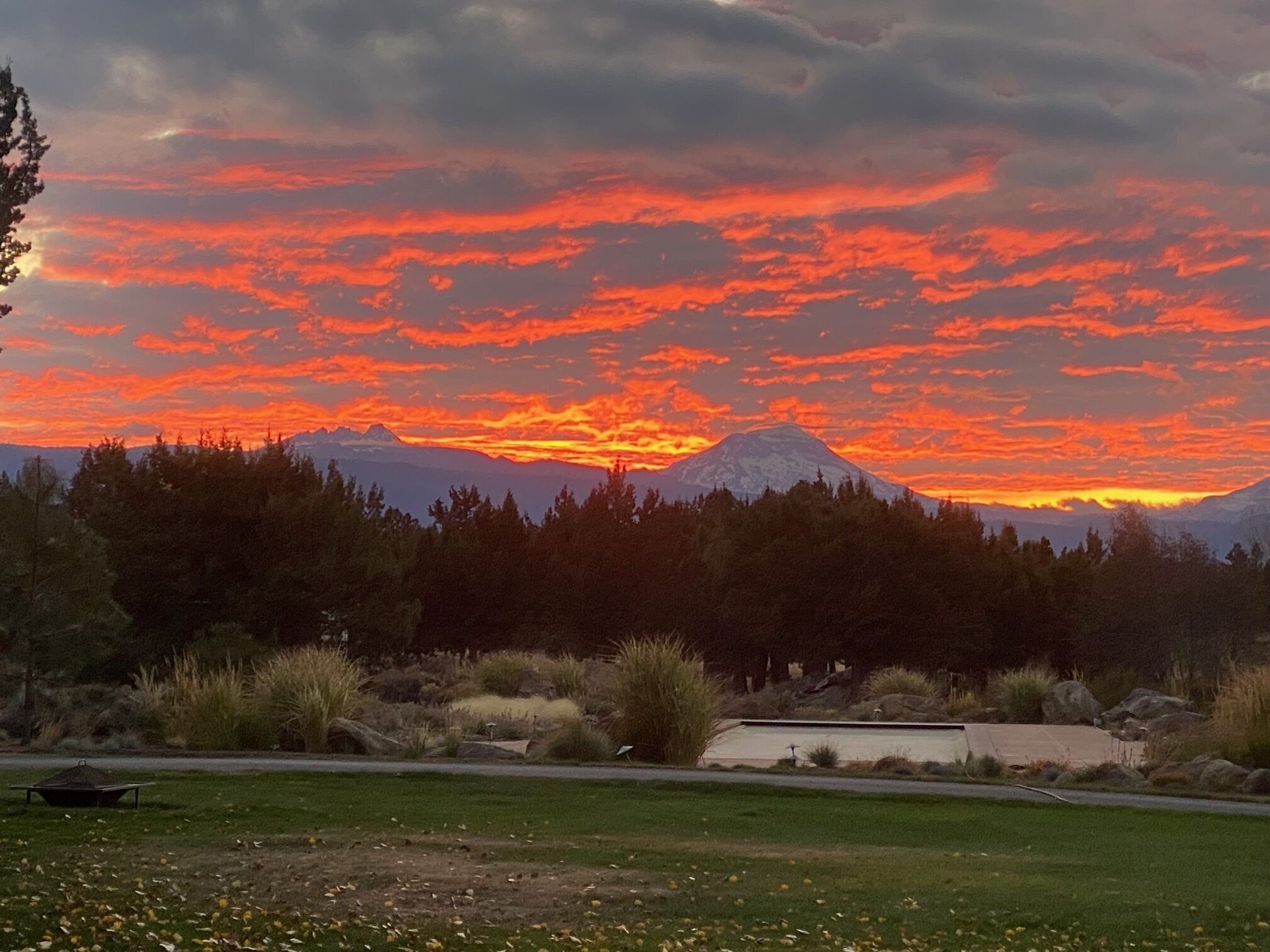 Un atardecer sobre una cadena montañosa con cielo despejado y un primer plano cubierto de hierba.