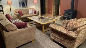 A cozy living room with two sofas, a coffee table, a fireplace, and a bookshelf.