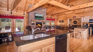 Un interior espacioso de cabaña de madera con una cocina grande, comedor y chimenea.