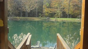 Une terrasse en bois qui mène à un lac paisible, bordé d’arbres aux couleurs automnales.