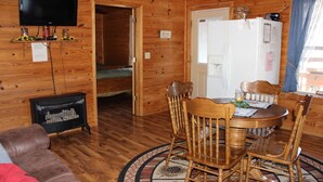 L’intérieur d’une cabane en bois comprend un coin repas, un téléviseur fixé au mur et un réfrigérateur.
