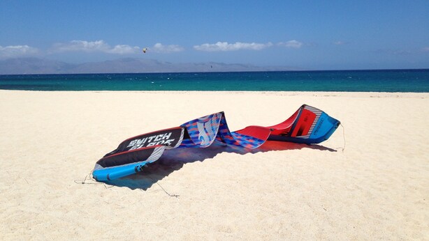 Una playa con una cometa sobre la arena.