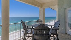 A balcony with a view of the ocean, featuring a table and four Adirondack chairs. - 3 Bdr Penthouse Unit Over the Polynesian Pool!! FREE BEACH CHAIRS!! (Panama City Beach)
