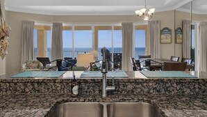 A modern kitchen with granite countertops, a double sink, and a view of the ocean. - 3 Bdr Penthouse Unit Over the Polynesian Pool!! FREE BEACH CHAIRS!! (Panama City Beach)
