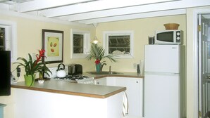 A compact kitchen with a central island, a microwave, a toaster, and a refrigerator. -  Cute Cozy Cottage with private entrance and ocean views in prime neighborhood (St. John)