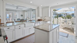 Una cocina amplia con armarios blancos, una isla grande y vista al patio exterior.