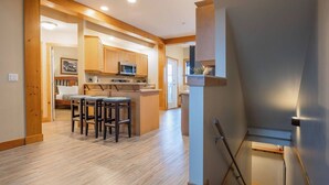 A modern kitchen with wooden cabinets, a central island with stools, and a built-in microwave.