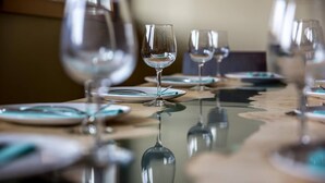 Una mesa de comedor con varias copas de vino y platos, con reflejos en la superficie.