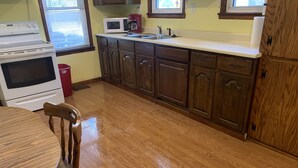 A kitchen with wooden cabinets, a white stove, a microwave, and a sink.