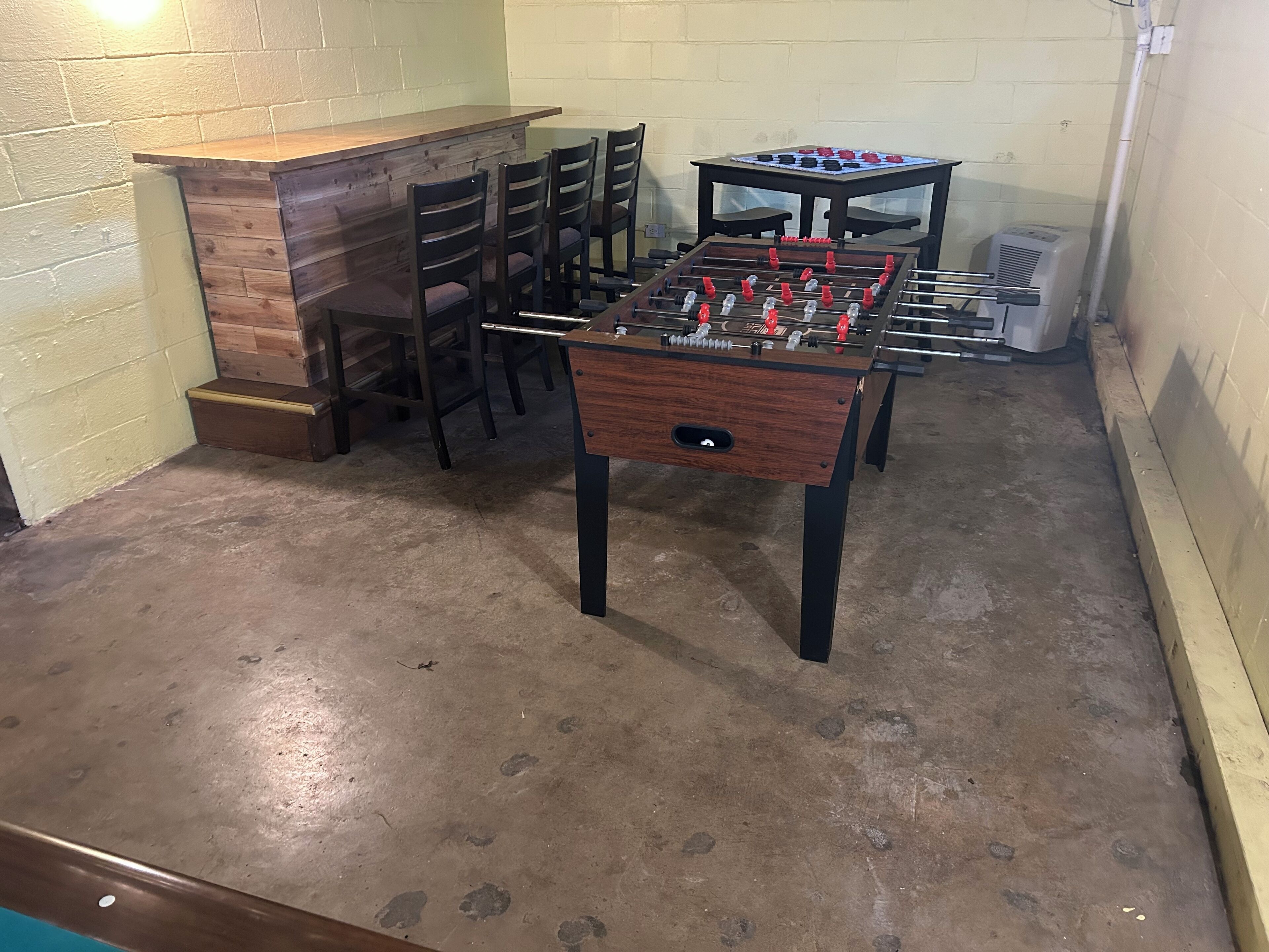 Ein Zimmer mit einer Fußballplatte, einem Billardtisch und mehreren Stühlen.