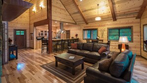 A spacious log cabin interior with a large living area, a kitchen, and a dining area. - Crystal Ridge, Wet Spa, Pool Table, Arcade Game, Hot Tub, Wood-burning Fireplace (Broken Bow)