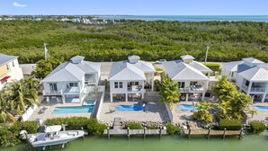 A resort with multiple buildings, a swimming pool, and a dock with a boat. - Canalside Retreat: 4Br, 3BA with Pool & Stunning Canal Views! (Marathon)