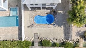 An aerial view of a resort with a large swimming pool, a wooden deck, and a dock. - Canalside Retreat: 4Br, 3BA with Pool & Stunning Canal Views! (Marathon)