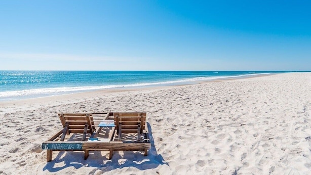 Une plage avec une terrasse en bois et des chaises longues, portant l’inscription « 6 ANDREWS ».
