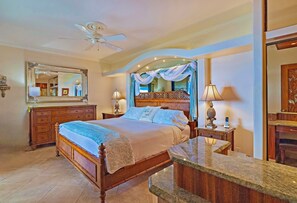 A bedroom with a wooden bed, a nightstand, a mirror, and a vanity with a marble countertop.