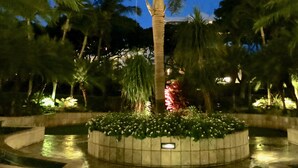 A well-lit circular garden with a central palm tree, surrounded by various plants and a paved walkway. - "Sunsational" Wailea Oceanfront-WOW Views over soft sand Beach a few steps away. (Makena  Maui)