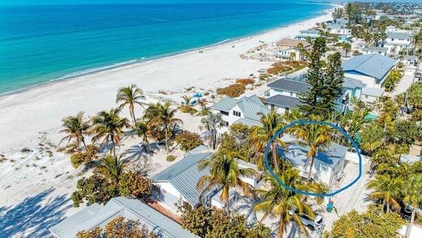 An aerial view of a coastal residential area with houses, a beach, and palm trees. - Pelican Perch: Tropical Paradise Cottage on the Beach            VRC17-000167 (Holmes Beach)