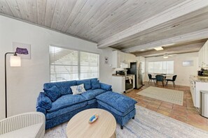 Una sala moderna con un sofá modular azul, una mesa de centro redonda y un comedor con mesa y sillas.