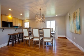 Enjoy meals in this dining area with a central table and six chairs, surrounded by a large window offering a view of the outdoors.