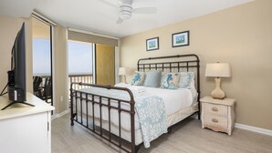 Ein Schlafzimmer mit Bett, Nachttischen, Fernseher und Deckenventilator.
