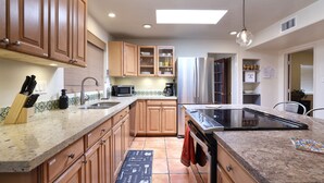 A modern kitchen with wooden cabinets, a stainless steel refrigerator, a microwave, and a stove. - Luxe Desert Escape: 15Min to Downtown ~ Pool ~ Spa ~ BBQ ~ Amazing desert views! (Tucson)