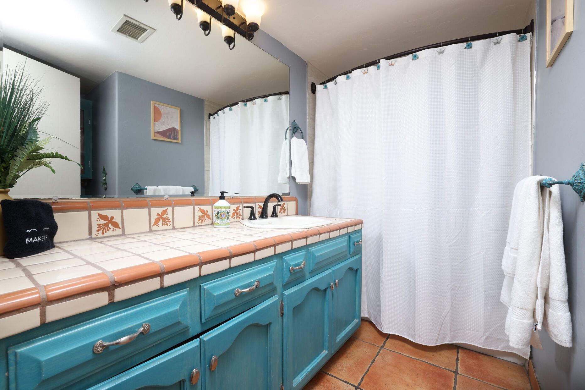 A bathroom with a sink, mirror, and a shower curtain.