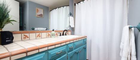 A bathroom with a sink, mirror, and a shower curtain.