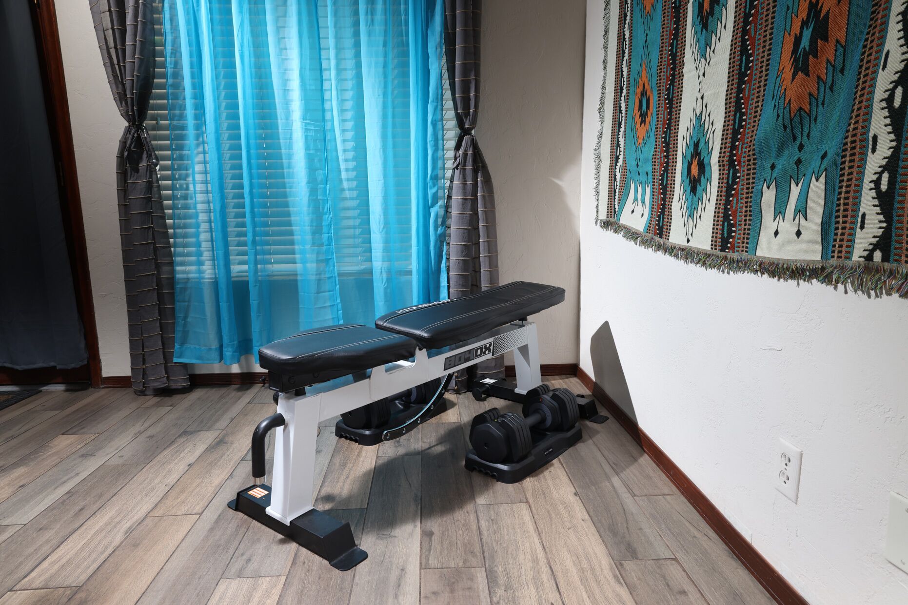 Une salle de sport à domicile équipée d’un banc de développé couché, d’un banc de musculation et d’un ensemble d’haltères.