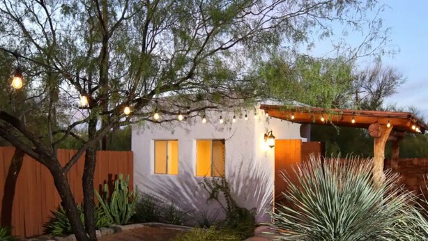 A house with a wooden fence, a small patio area, and string lights. - Luxe Desert Escape: 15Min to Downtown ~ Pool ~ Spa ~ BBQ ~ Amazing desert views! (Tucson)
