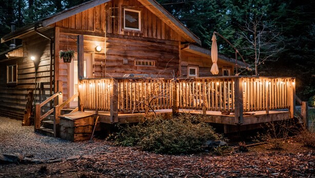 A wooden cabin with a porch, steps, and a small window.