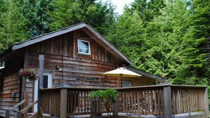 A wooden cabin with a deck and a small porch.